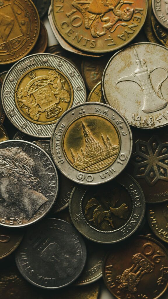 Hand dropping a coin into a piggy bank surrounded by coins