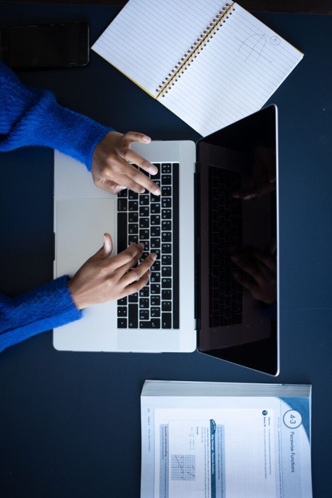 Hands typing on a laptop keyboard, top-down view