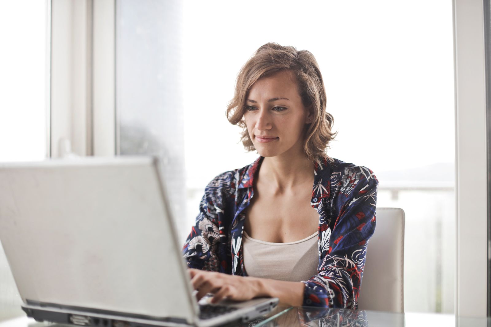Writer working on a laptop by a bright window